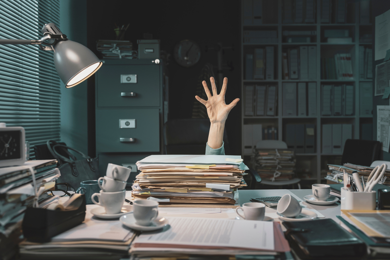 business worker overwhelmed with paperwork and coffee cups
